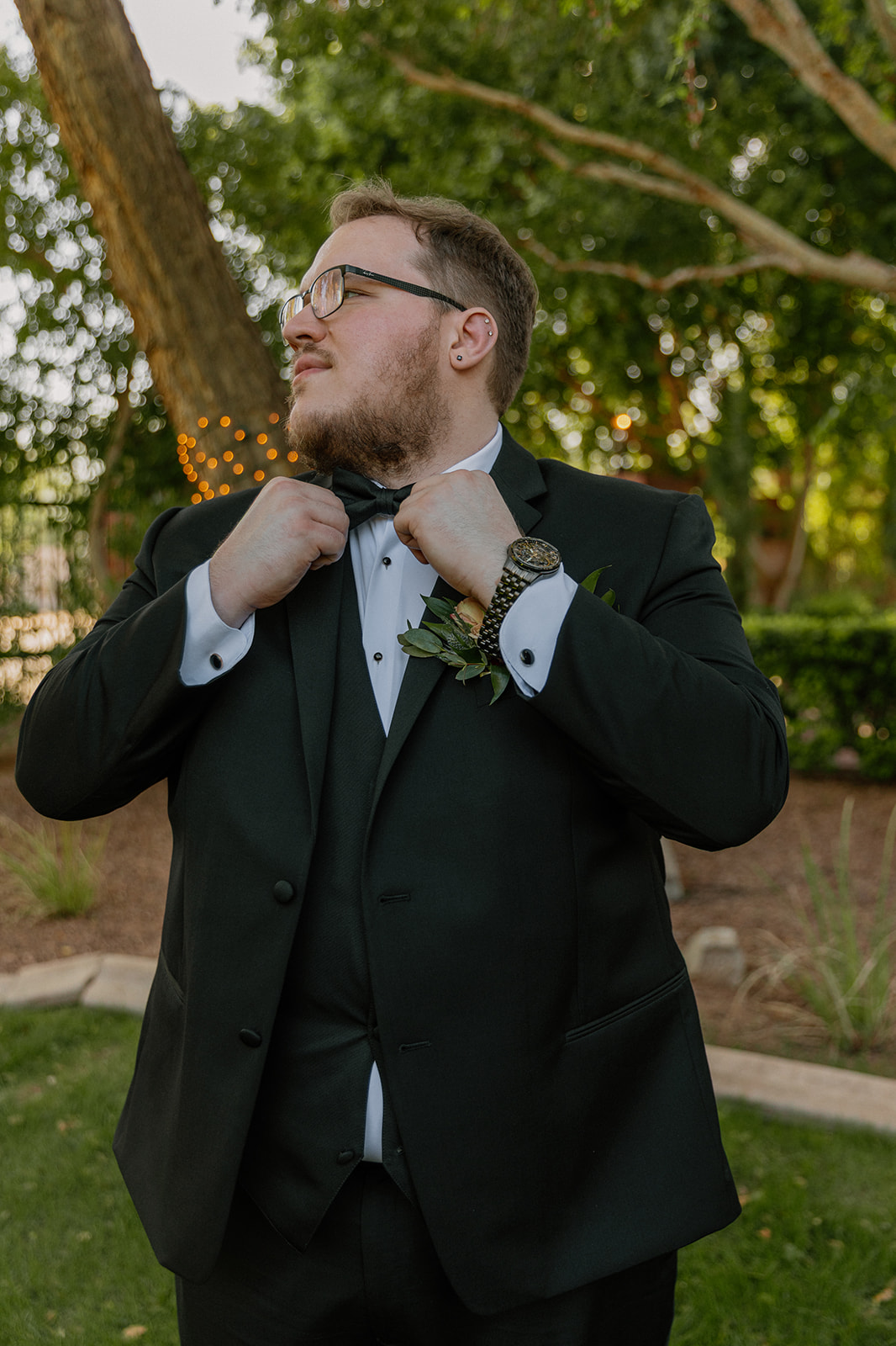 Groom adjusting bow tie during wedding portraits at Stonebridge Manor Wedding Venue