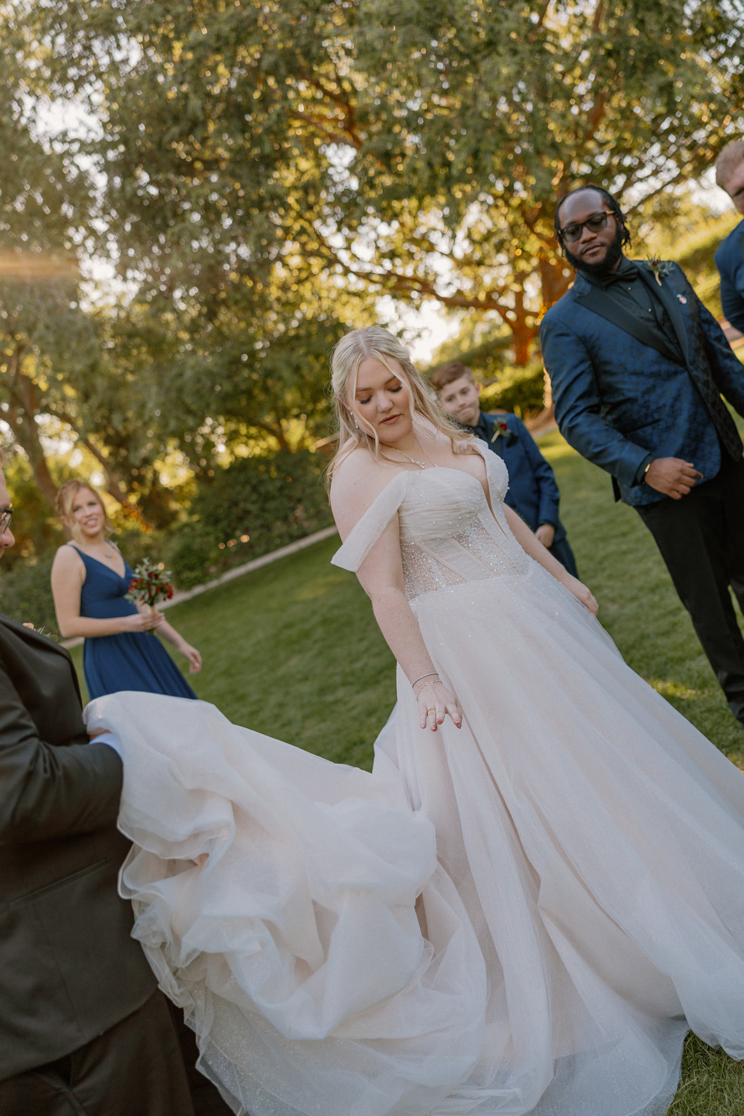 Bride adjusting wedding dress during golden hour portraits on the lawn

