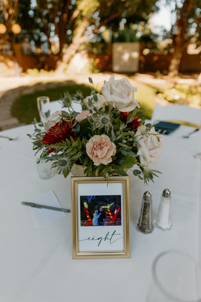 Wedding reception centerpiece with floral arrangement and table number at Stonebridge Manor Wedding Venue