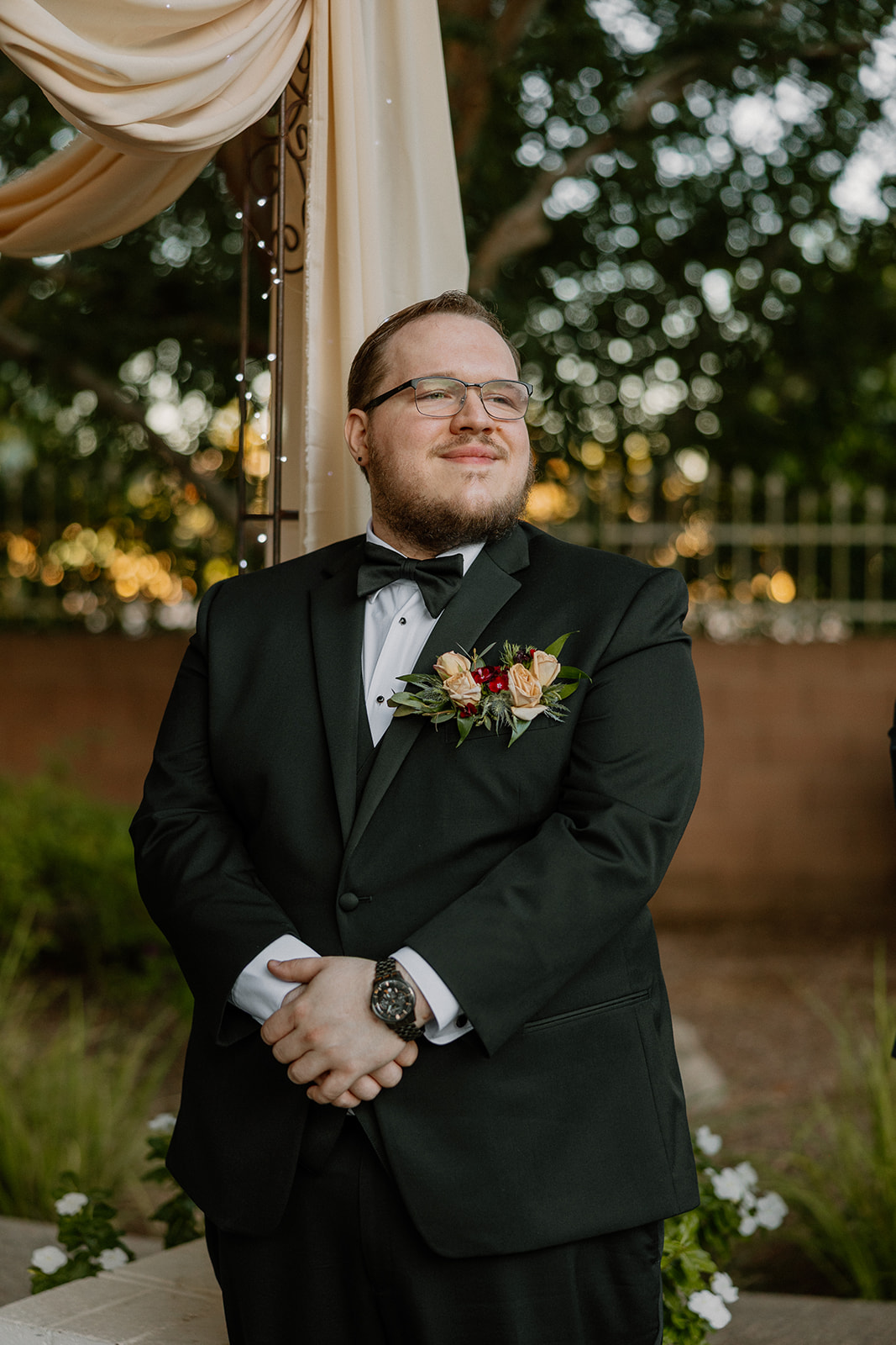 Groom waiting at ceremony arch during outdoor wedding at Stonebridge Manor in Mesa Arizona