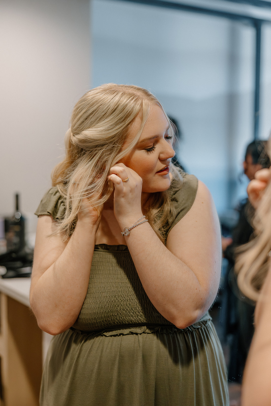 Bridesmaid putting on earrings while getting ready for wedding