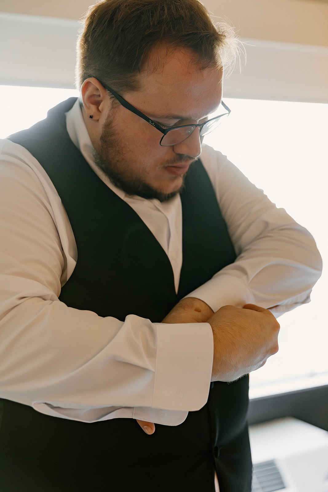 Groom adjusting cufflinks while getting dressed before ceremony