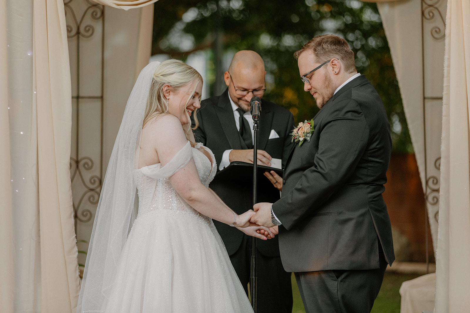 Bride and groom holding hands during wedding vows at outdoor Stonebridge Manor ceremony