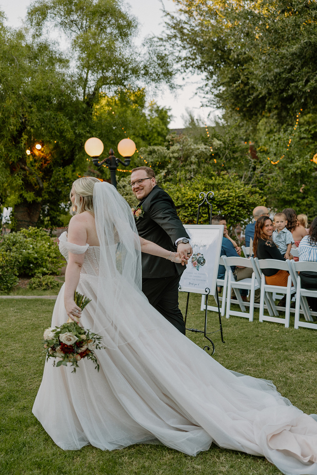 Newlyweds walking toward ceremony seating across the lawn at Stonebridge Manor Wedding Venue