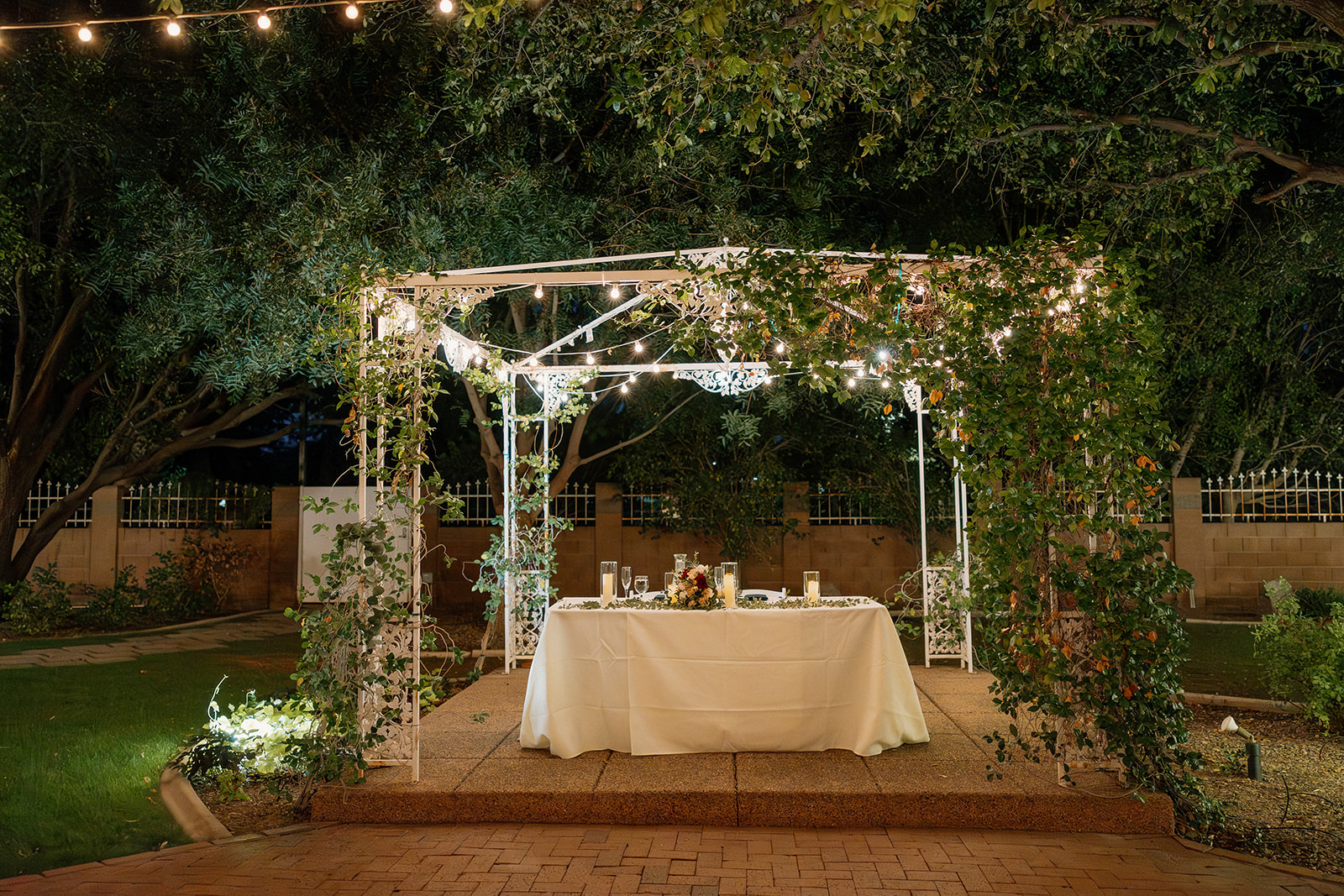 Romantic head table under vine-covered pergola at Stonebridge Manor Wedding Venue at night