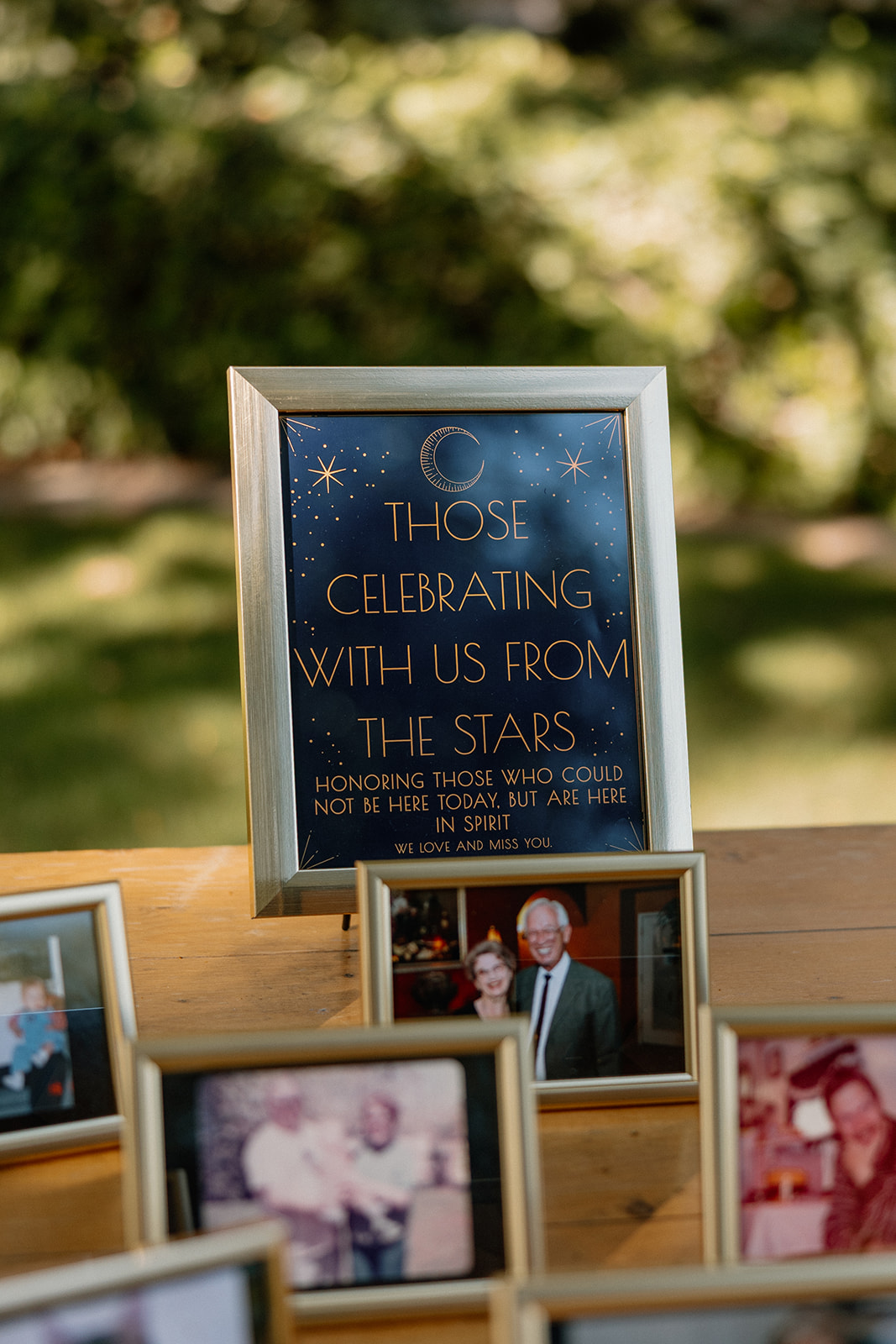 Wedding memorial table honoring loved ones with framed photos and sign