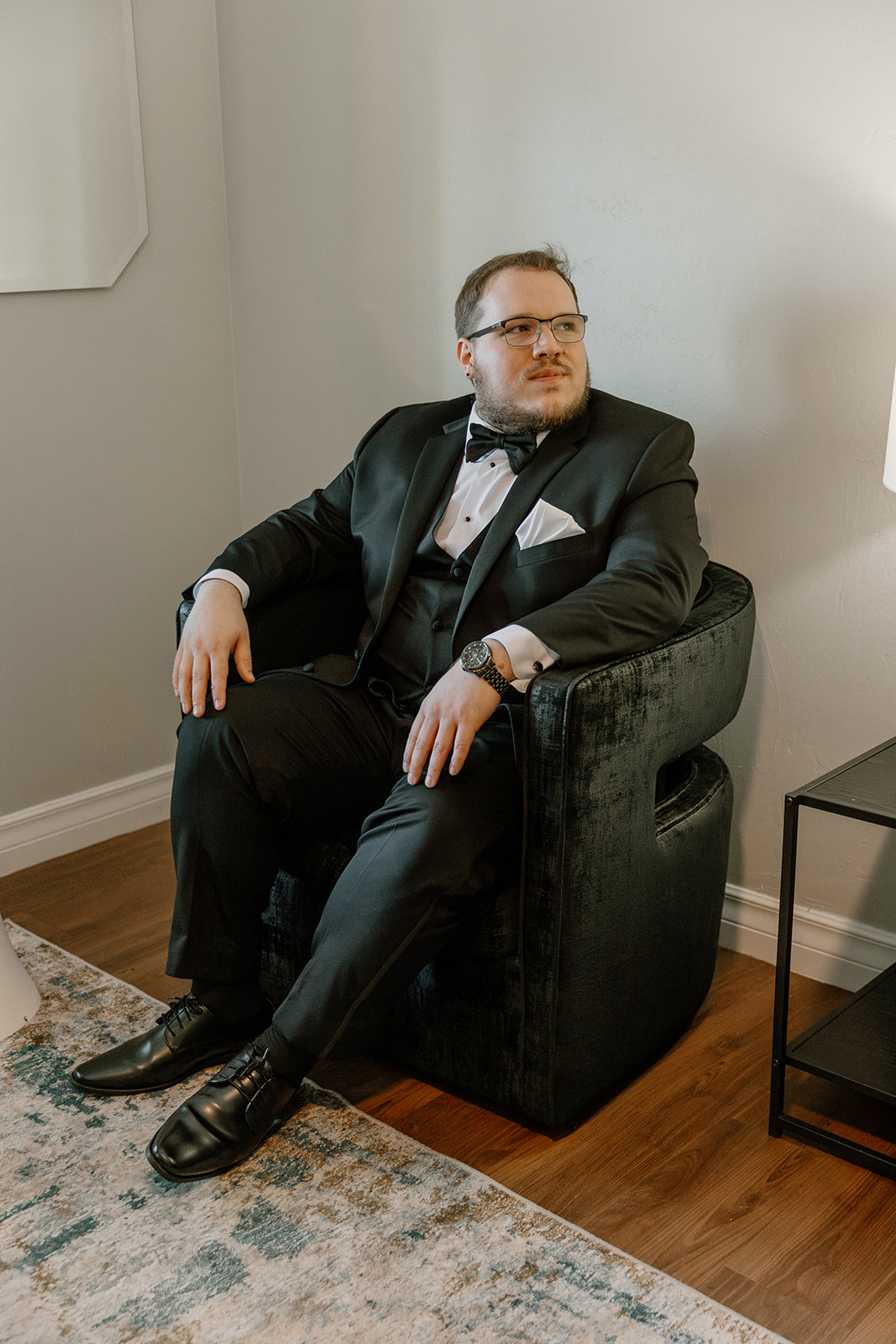 Groom sitting in chair while getting ready for wedding at Stonebridge Manor Wedding Venue