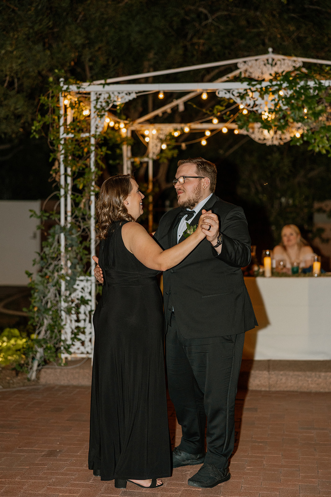 Mother and groom sharing a dance under string lights at the Stonebridge Manor Wedding Venue patio