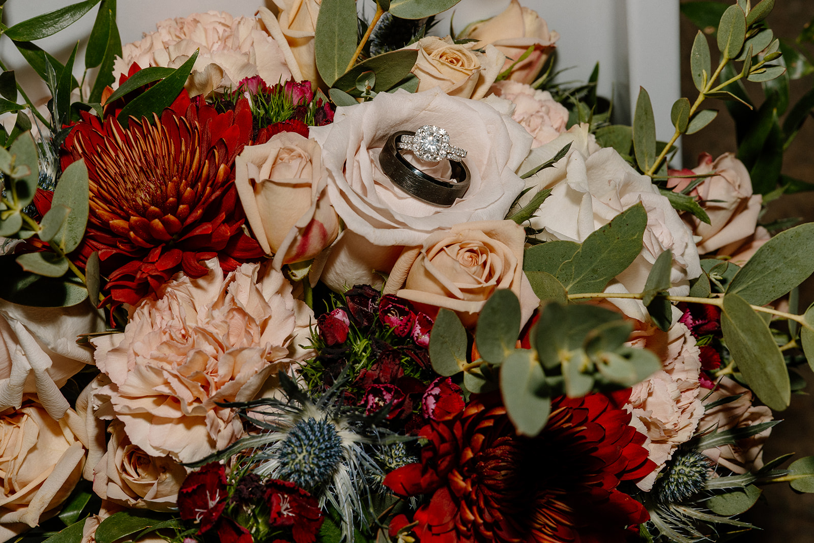 Wedding rings resting on bouquet with roses and greenery at Stonebridge Manor Wedding Venue