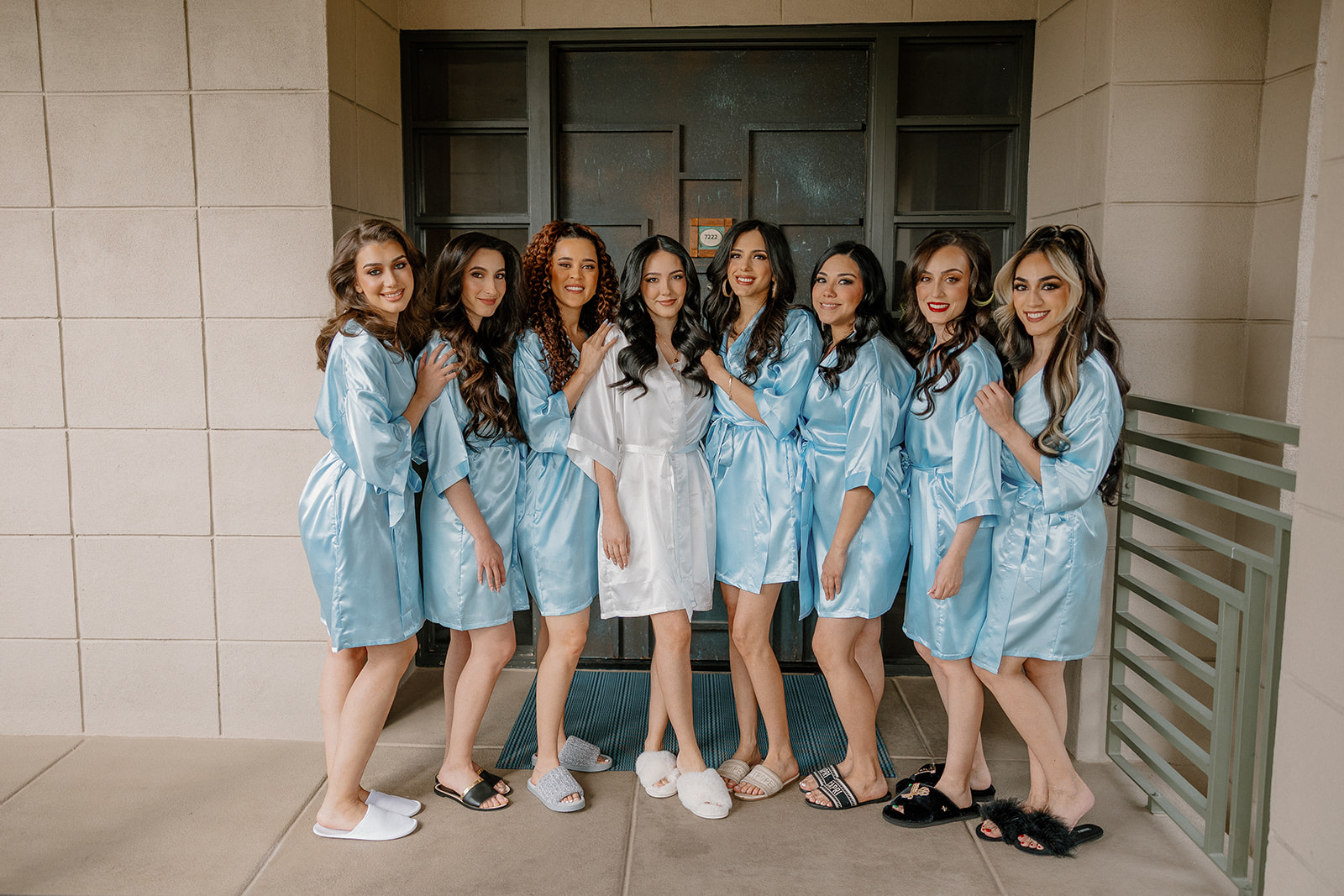 Bride and bridesmaids in matching robes standing together before getting ready
