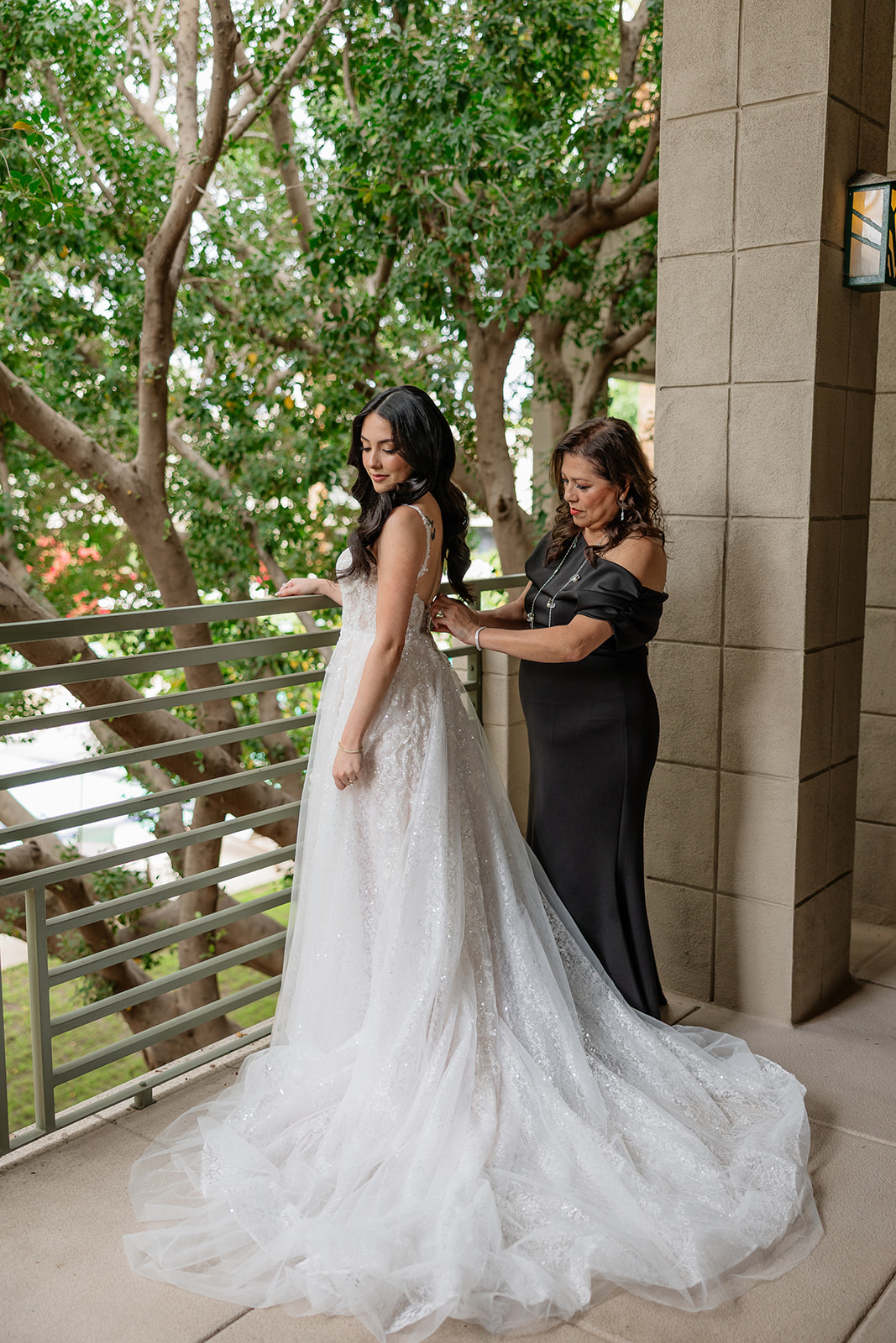 Bride getting her dress zipped up by her mom on a balcony during the Biltmore wedding
