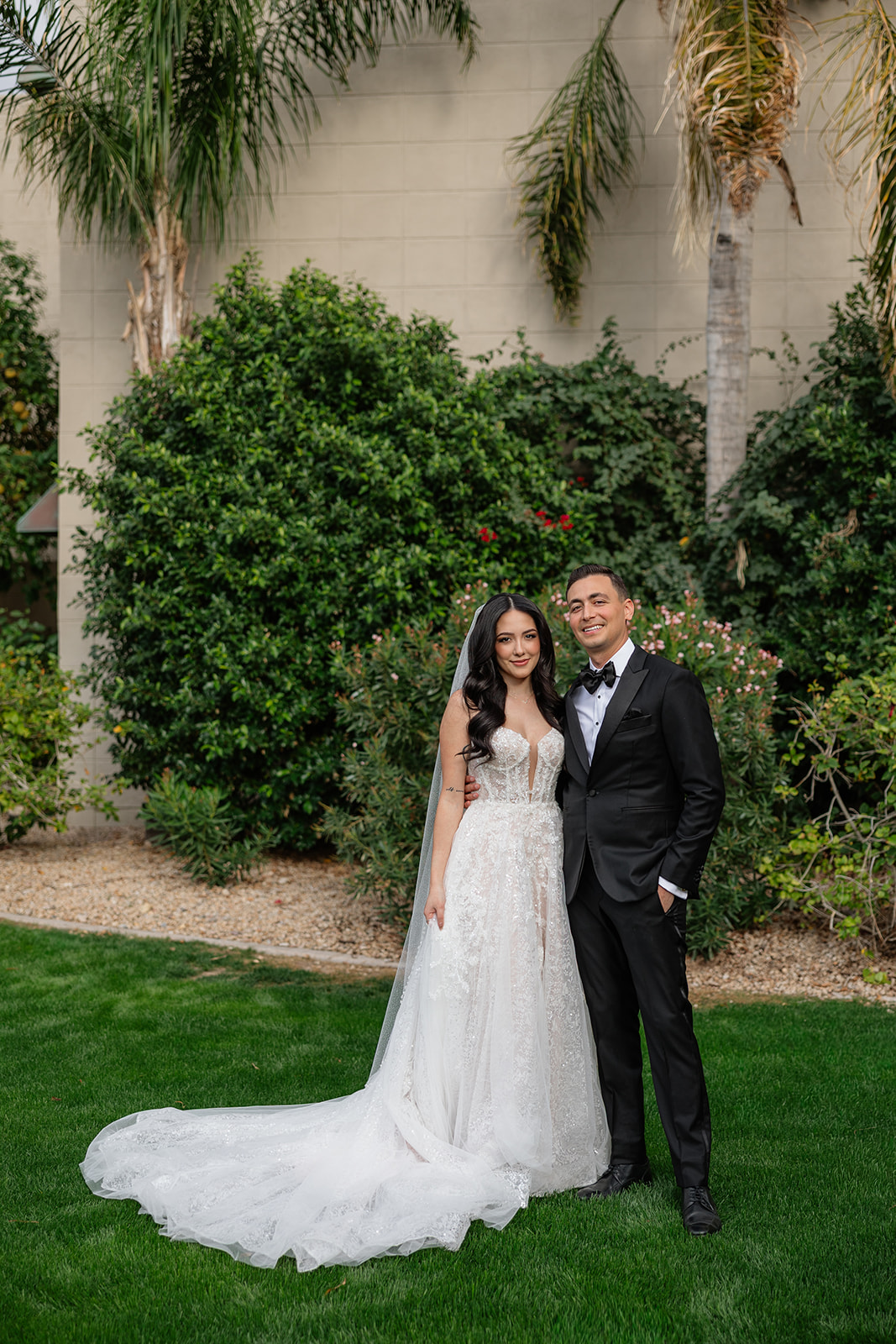 Bride and groom standing together on the lawn surrounded by greenery during their Biltmore wedding portraits
