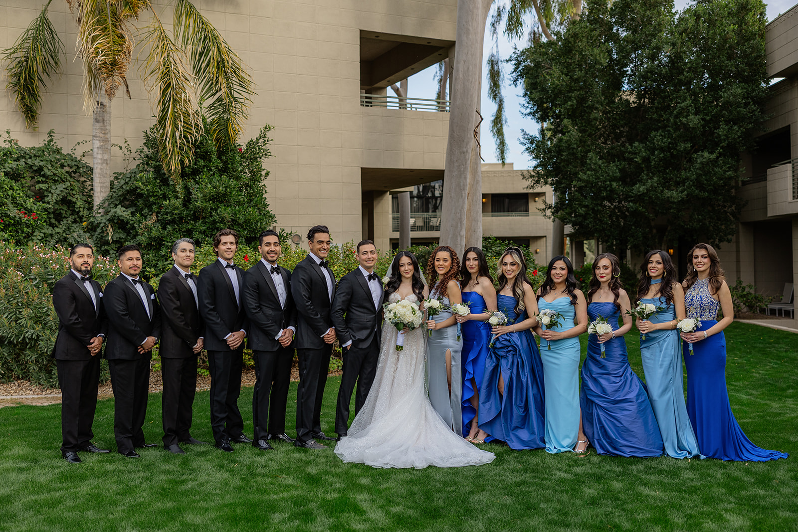 Full wedding party standing together on the lawn with bridesmaids in blue dresses and groomsmen in black suits at a Biltmore wedding
