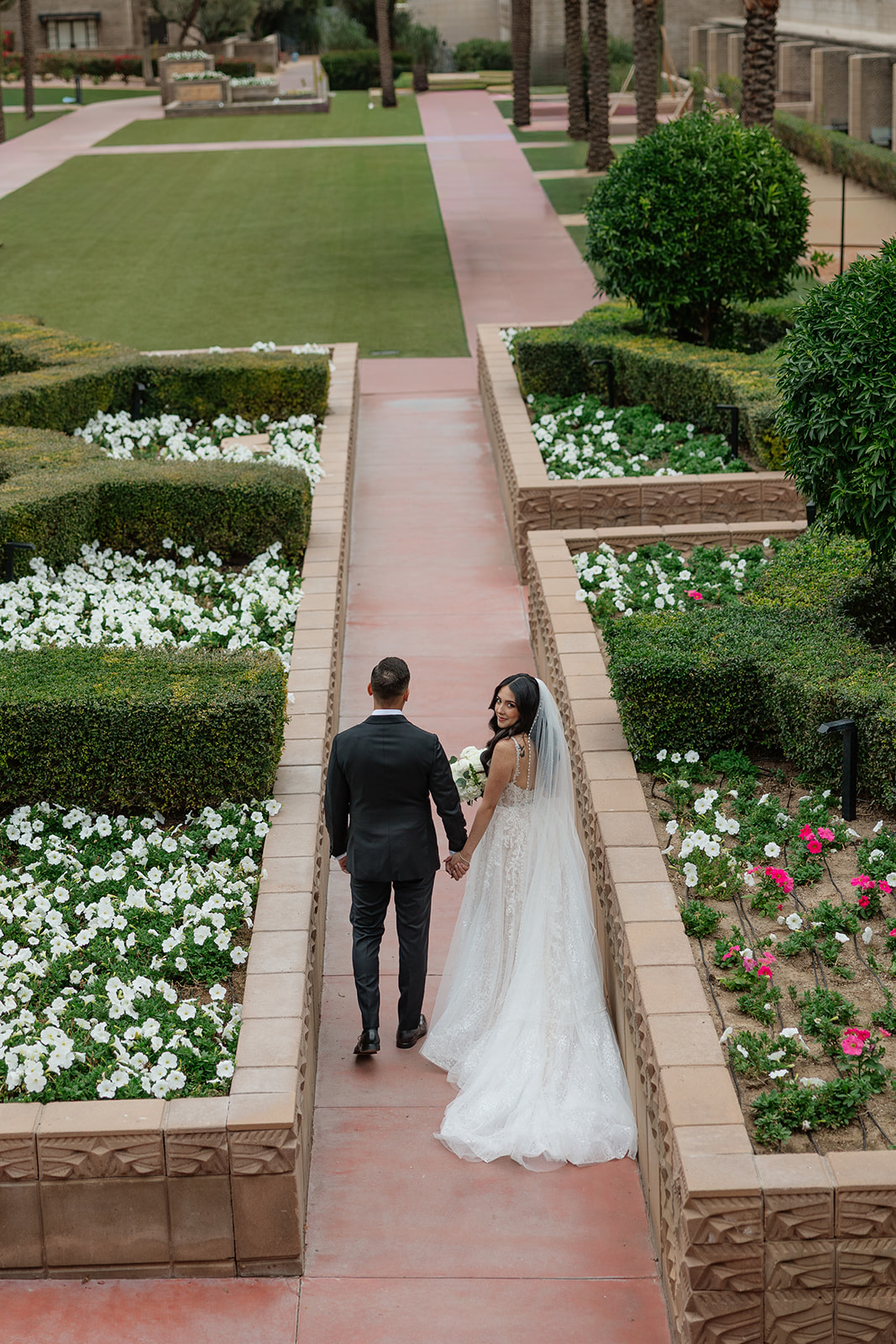 Bride and groom walking hand in hand through the garden paths at the Biltmore wedding venue
