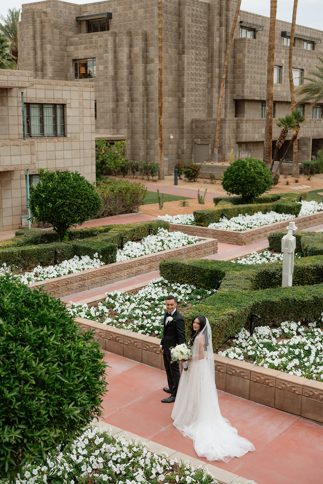 Bride and groom standing in a garden courtyard with geometric landscaping at the Biltmore wedding venue
