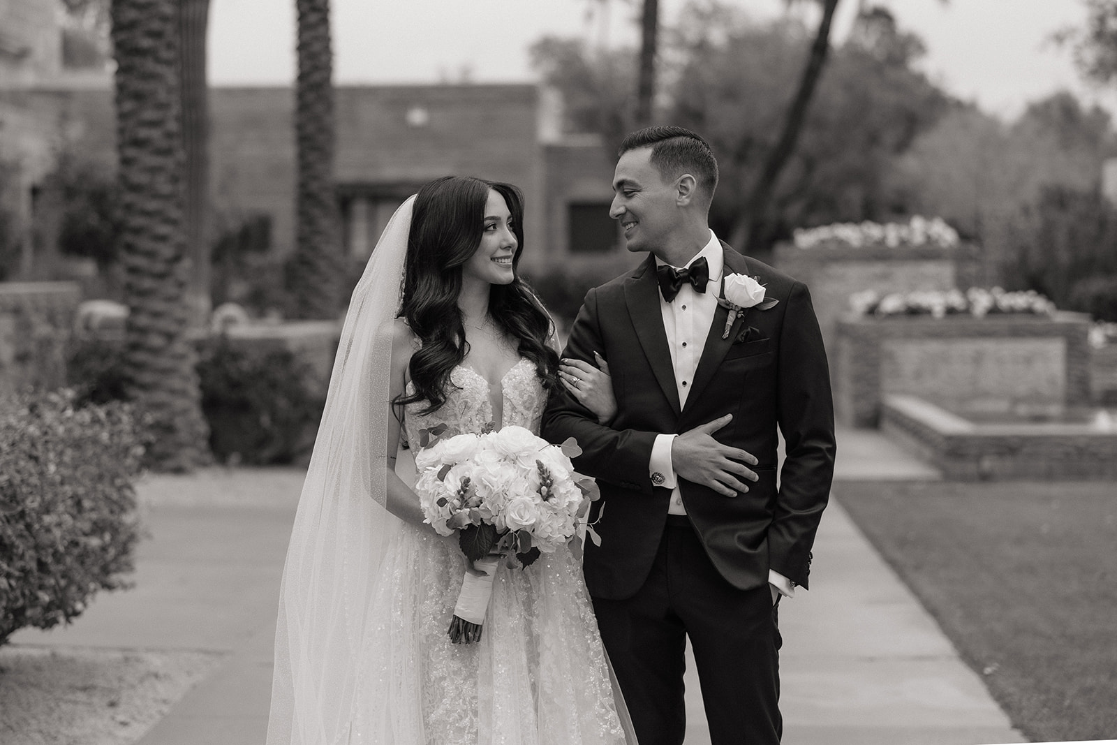 Black and white portrait of the couple walking together and smiling during their Biltmore wedding portraits
