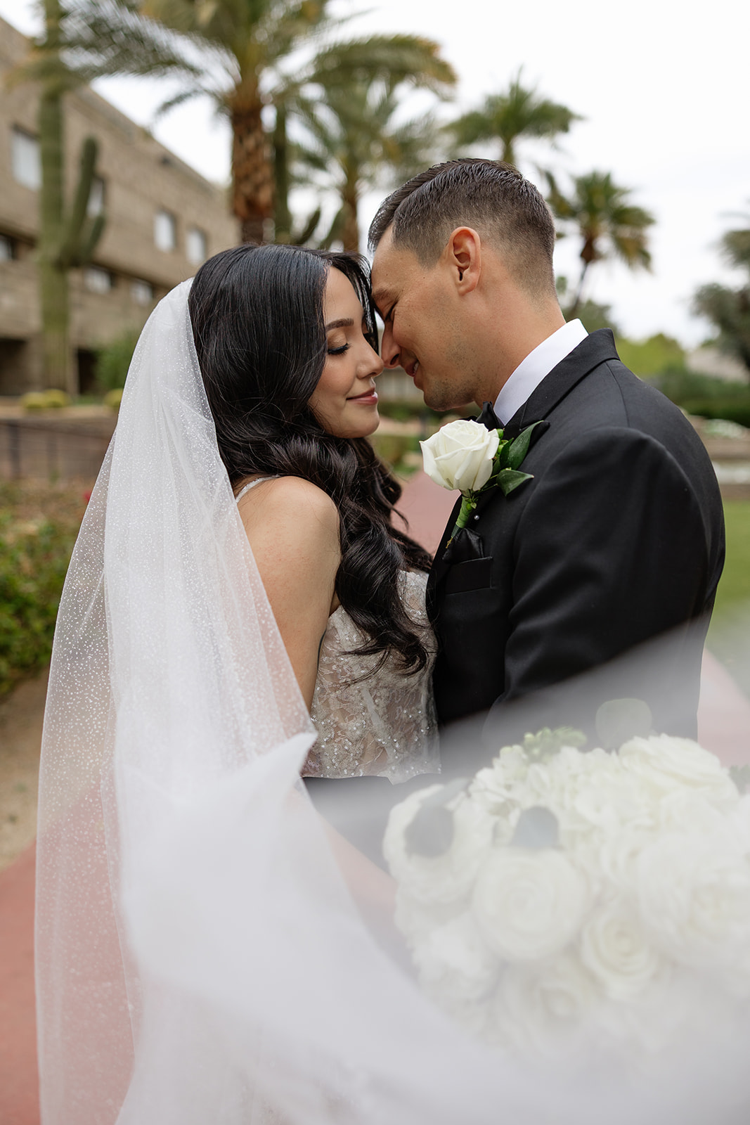Close-up of bride and groom leaning in together, foreheads touching during an outdoor portrait
