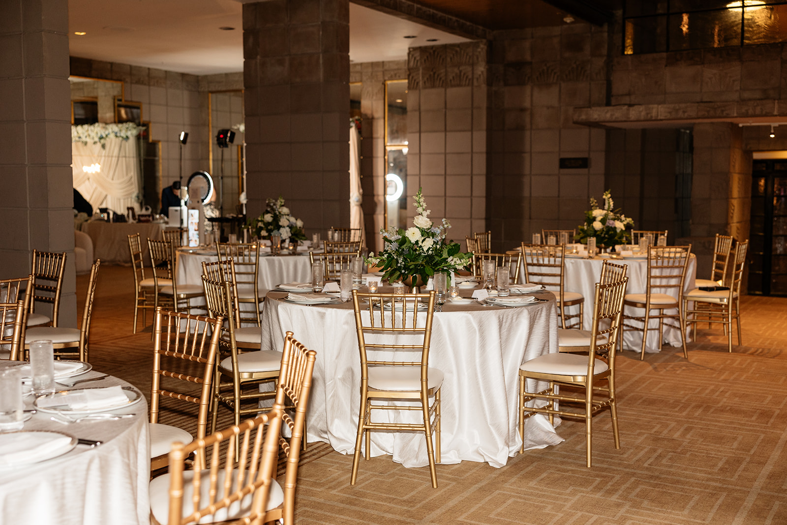 Reception space with round tables, white linens, and gold chairs set for a Biltmore wedding
