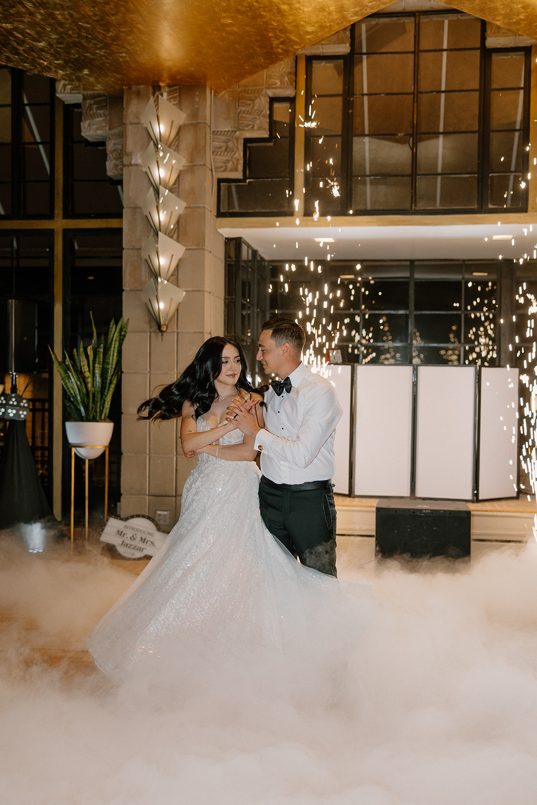 Bride and groom dancing together with indoor sparklers and low fog on the dance floor
