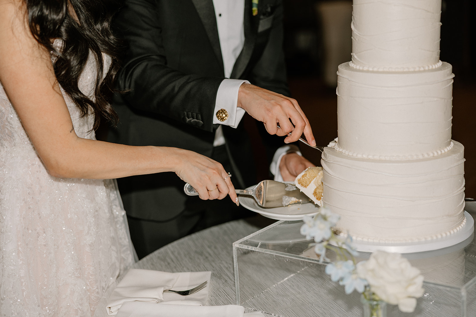 Bride and groom cutting a white tiered cake together during their Biltmore wedding reception
