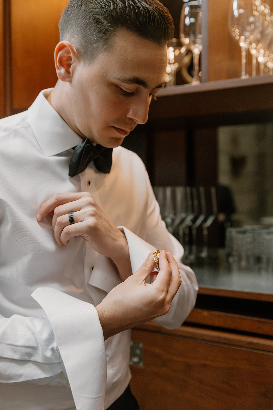 Groom adjusting his cufflinks while getting ready indoors before the ceremony
