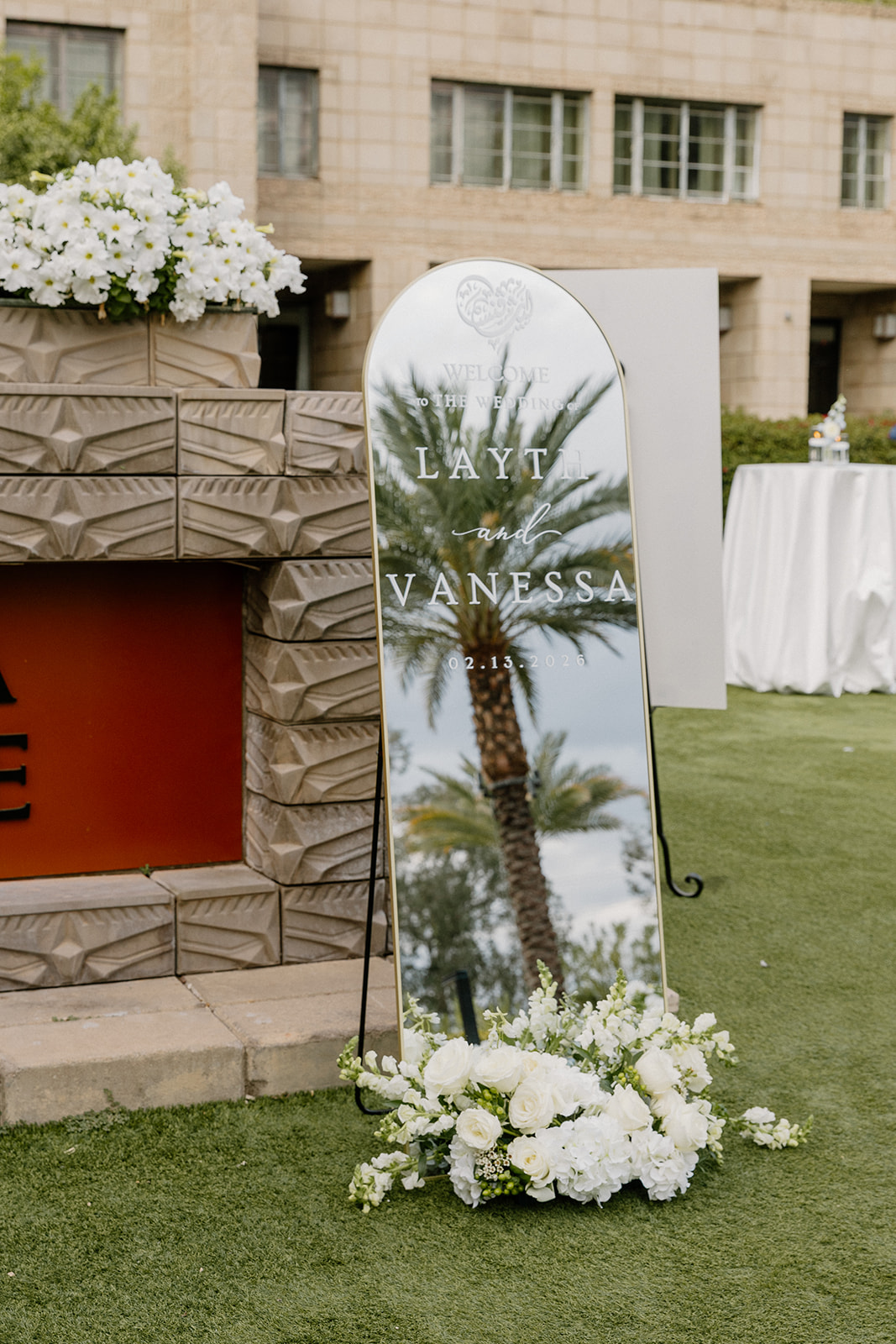 Mirrored welcome sign with floral arrangement reflecting palm trees at a Biltmore wedding
