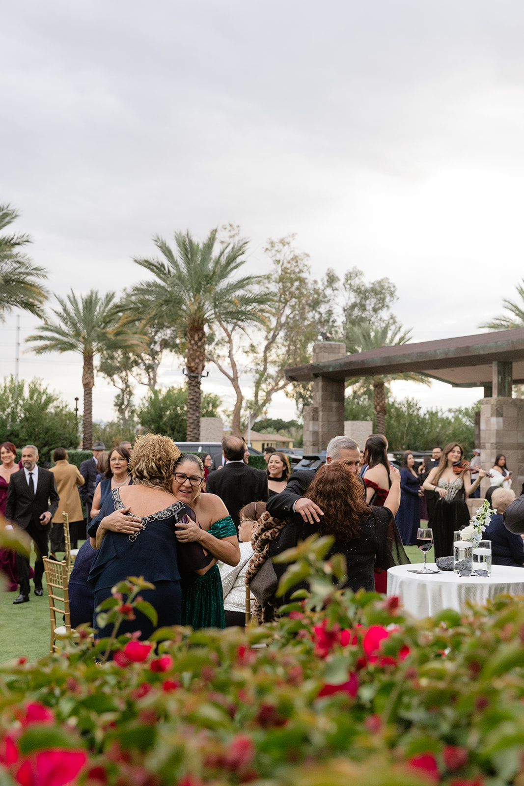 Guests greeting each other and hugging during cocktail hour with palm trees in the background

