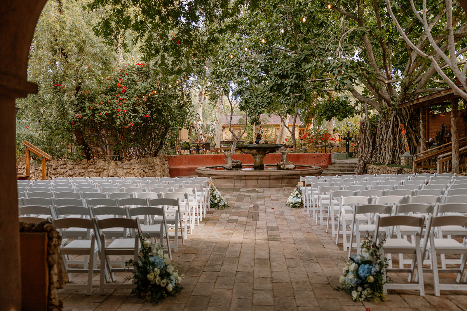 Outdoor wedding ceremony aisle with white chairs and fountain backdrop at Arizona garden venue
