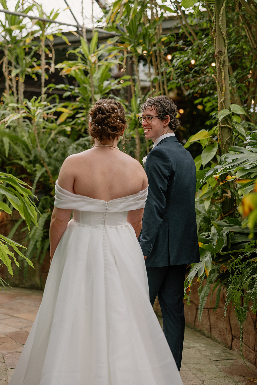 Bride and groom walking hand in hand through lush garden pathway at Arizona wedding venues
