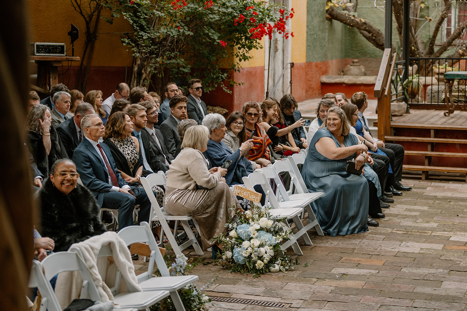 Wedding guests seated in courtyard ceremony space with florals and reserved seating at Arizona wedding venues
