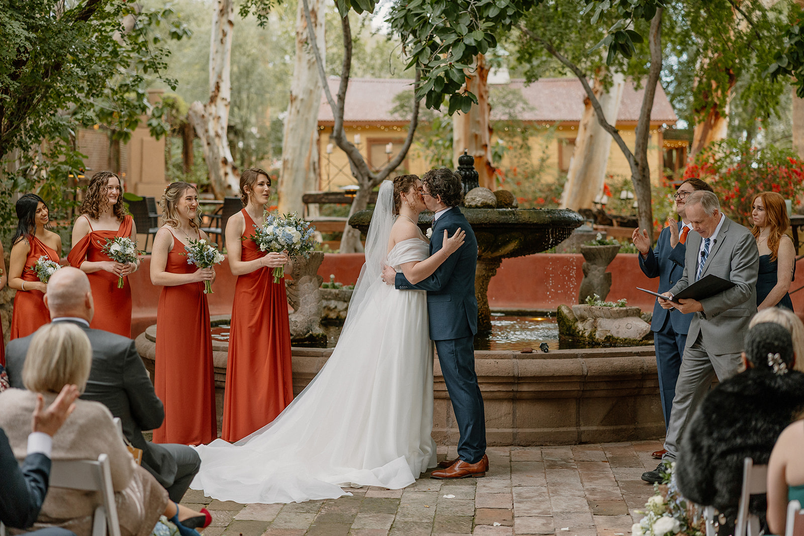 Bride and groom kissing during outdoor ceremony at Arizona wedding venues with fountain backdrop
