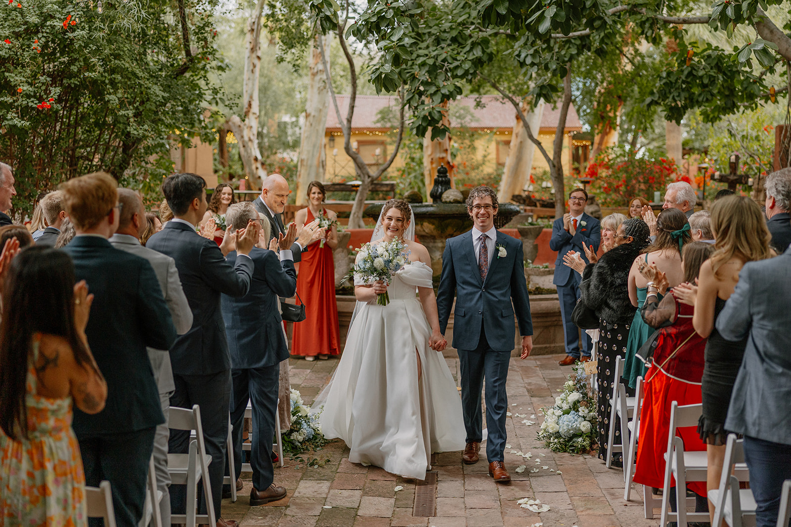Bride and groom walking down the aisle after ceremony surrounded by guests in a garden Arizona wedding venue

