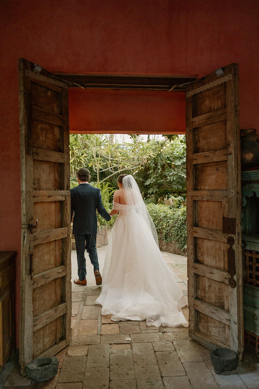 Newlyweds walking through rustic wooden doors into garden courtyard at a scenic Arizona wedding venue
