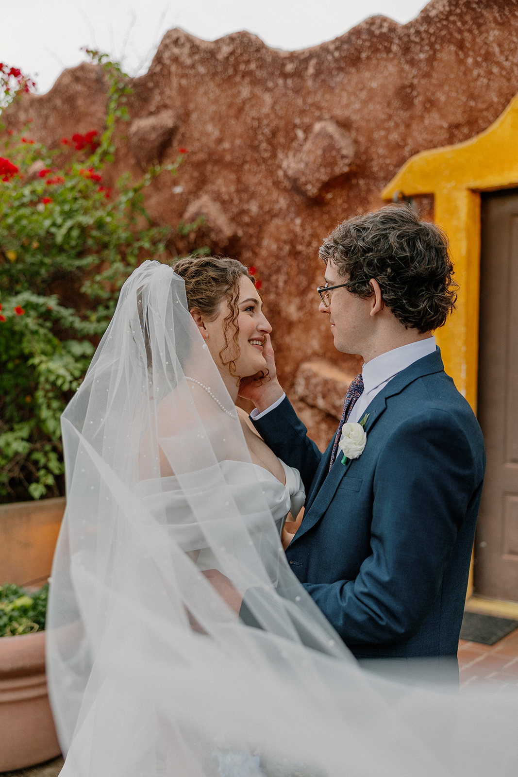 Bride and groom sharing intimate moment outdoors at Arizona wedding venue with colorful adobe walls
