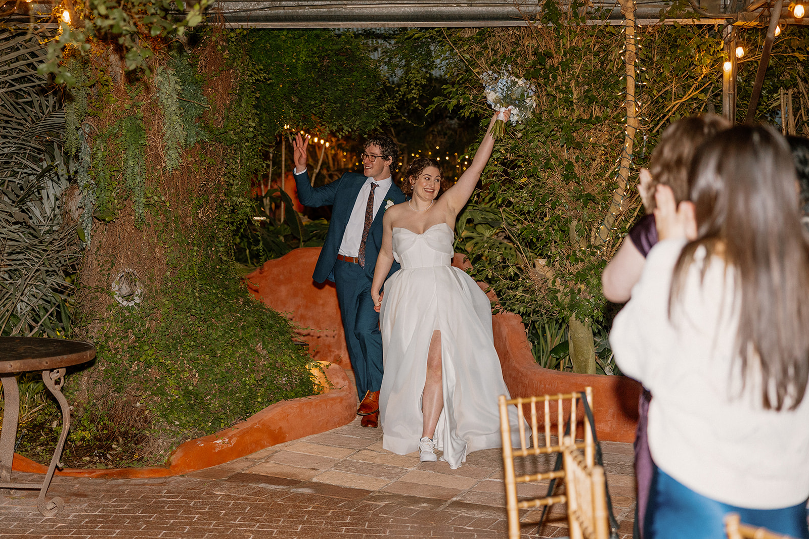 Newlyweds making a grand entrance into reception space at Arizona wedding venues with lush greenery and warm lighting
