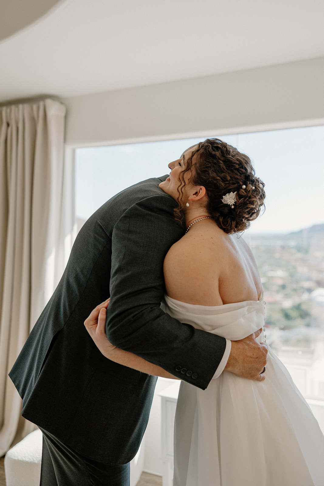 Bride hugging family member in bright modern home with desert mountain views before ceremony

