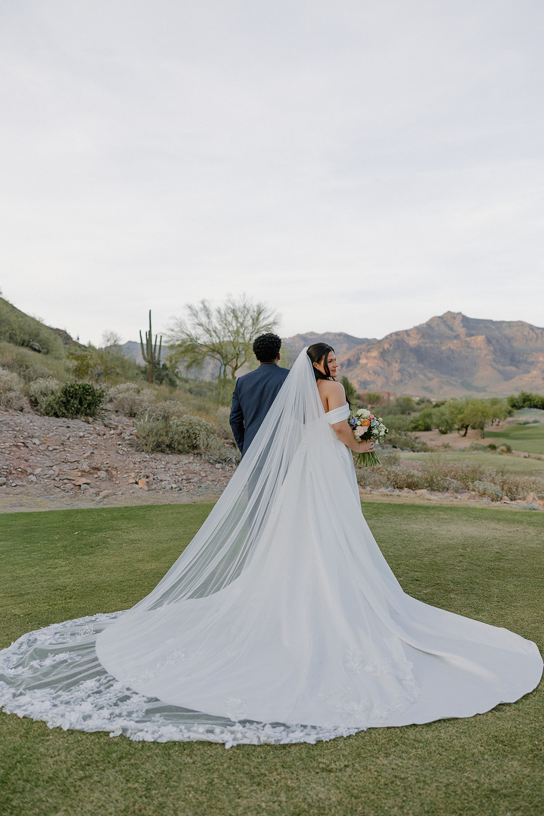 bride standing with long veil flowing behind her on golf course at gold canyon golf resort wedding