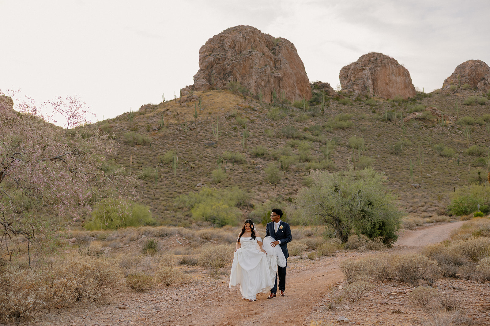 bride and groom walking together on desert trail surrounded by arizona mountains