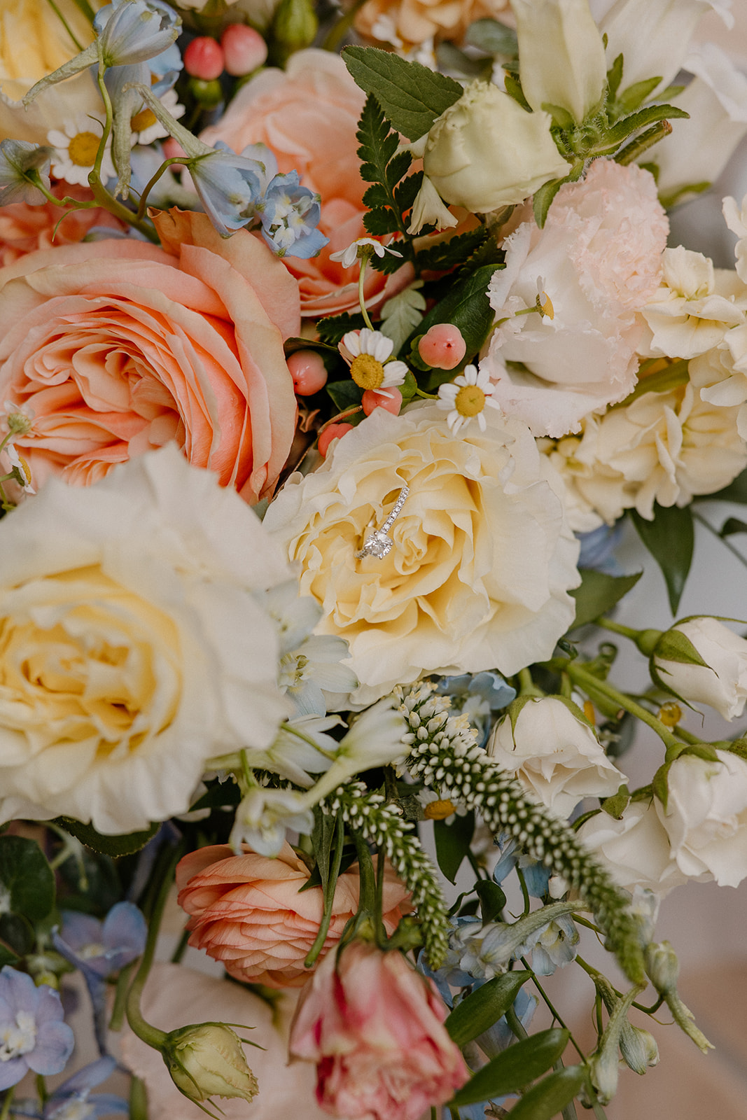 close up of wedding bouquet with peach and cream flowers and greenery