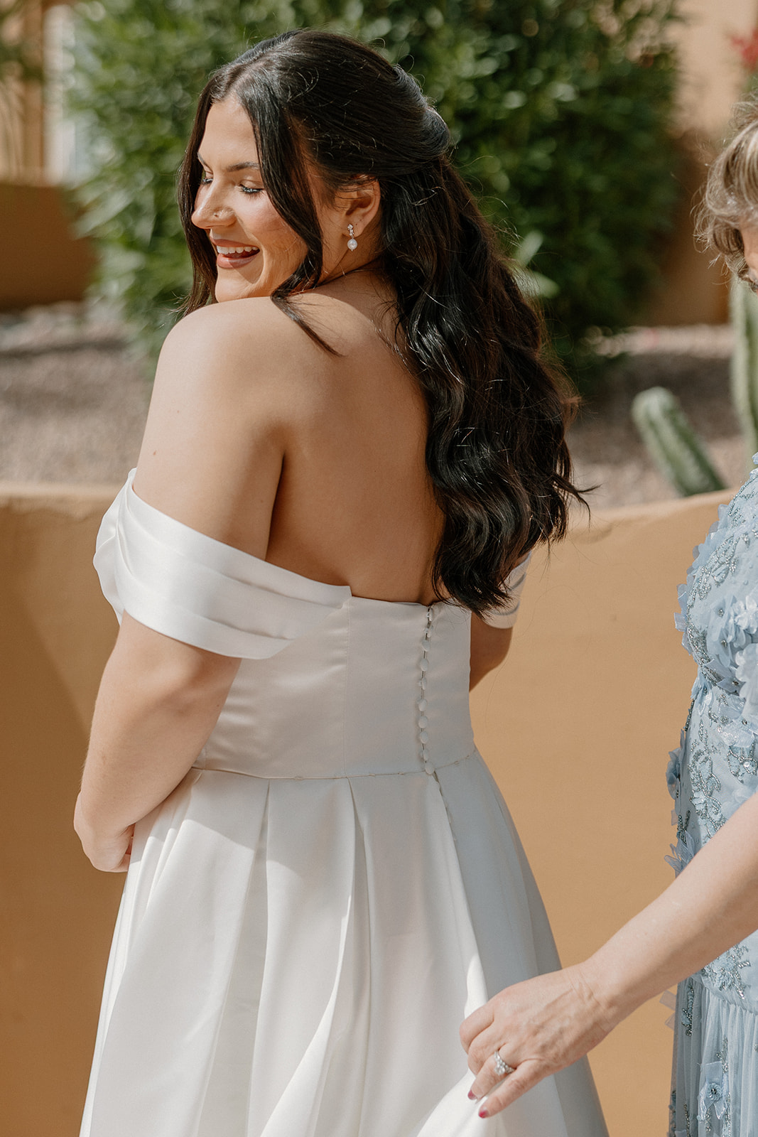 close up of bride smiling while getting ready with off shoulder wedding dress
