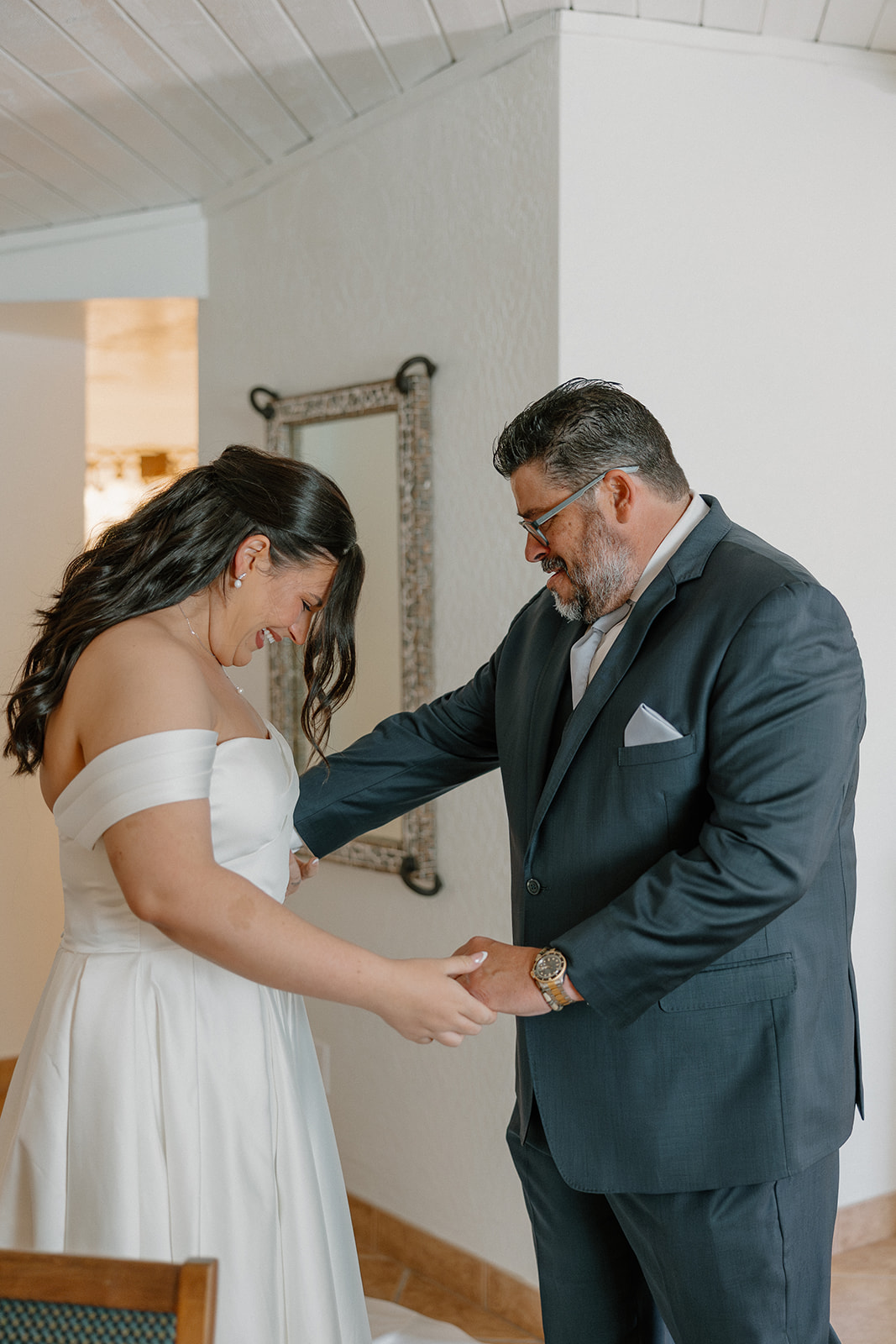 father helping bride with dress during getting ready moment indoors
