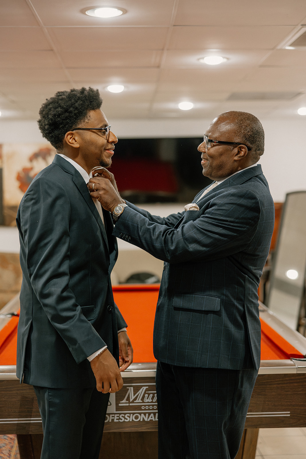 groom getting ready with family member adjusting tie indoors before ceremony