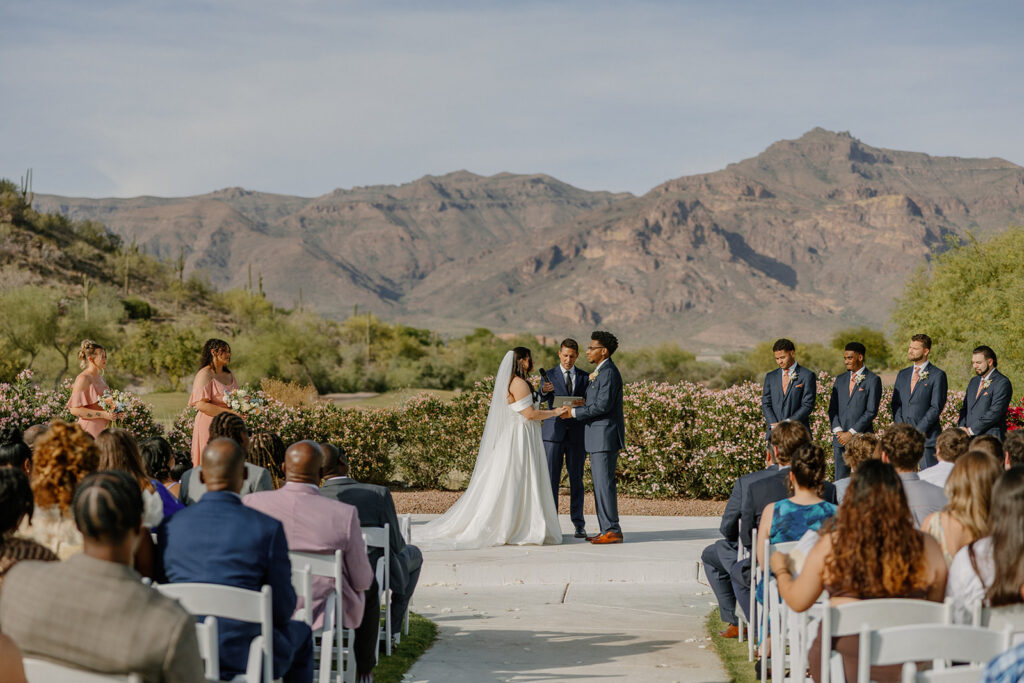 bride and groom standing together during ceremony with guests seated and mountain views at gold canyon golf resort wedding