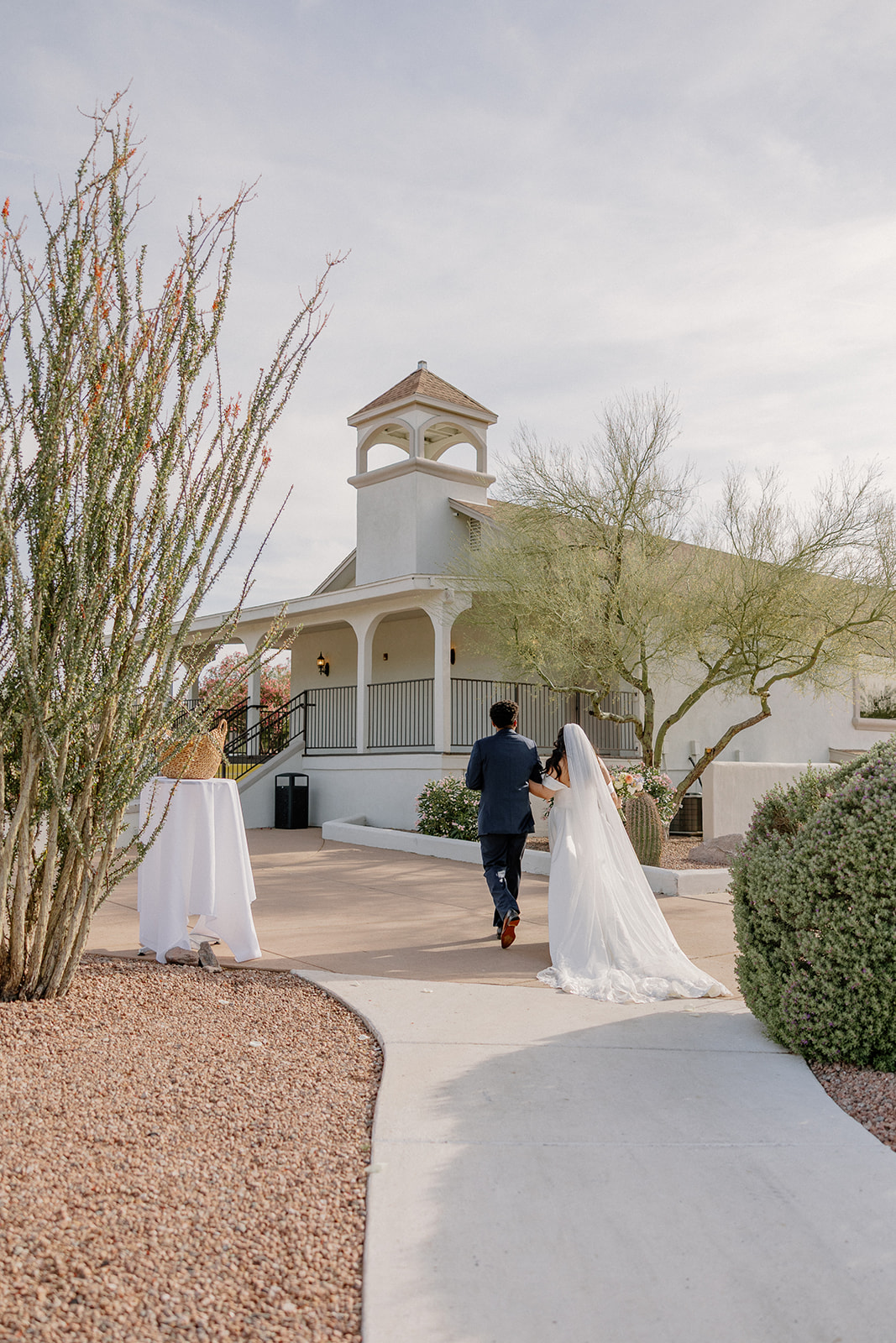 bride and groom walking together toward reception space with desert architecture