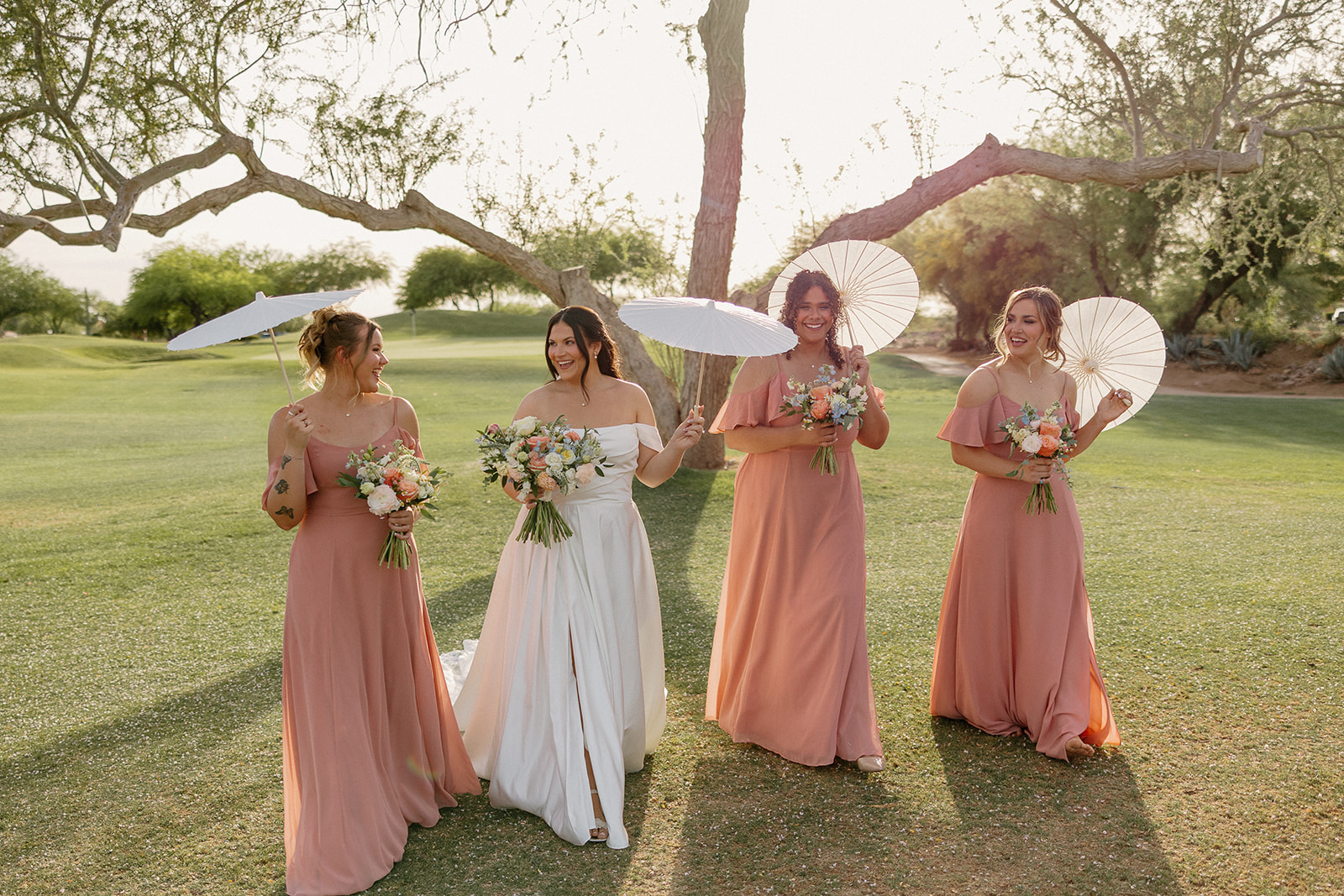 bride and bridesmaids holding parasols during golden hour portraits outdoors