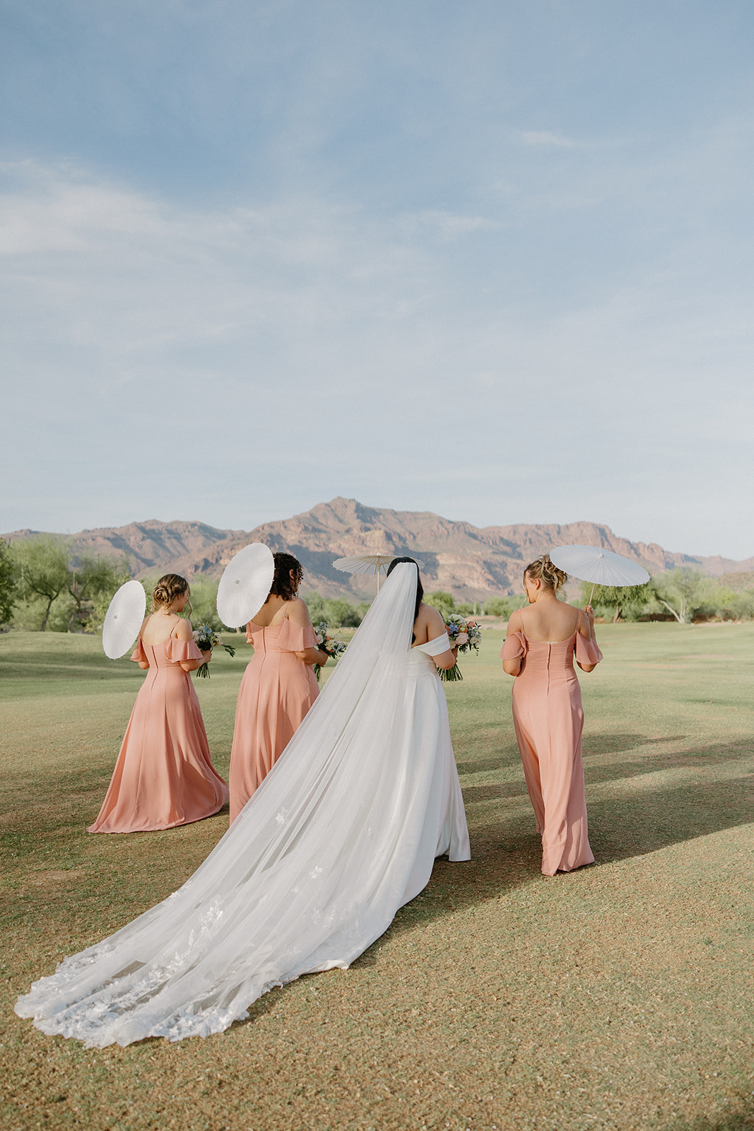 bride and bridesmaids walking across golf course with parasols at gold canyon golf resort wedding