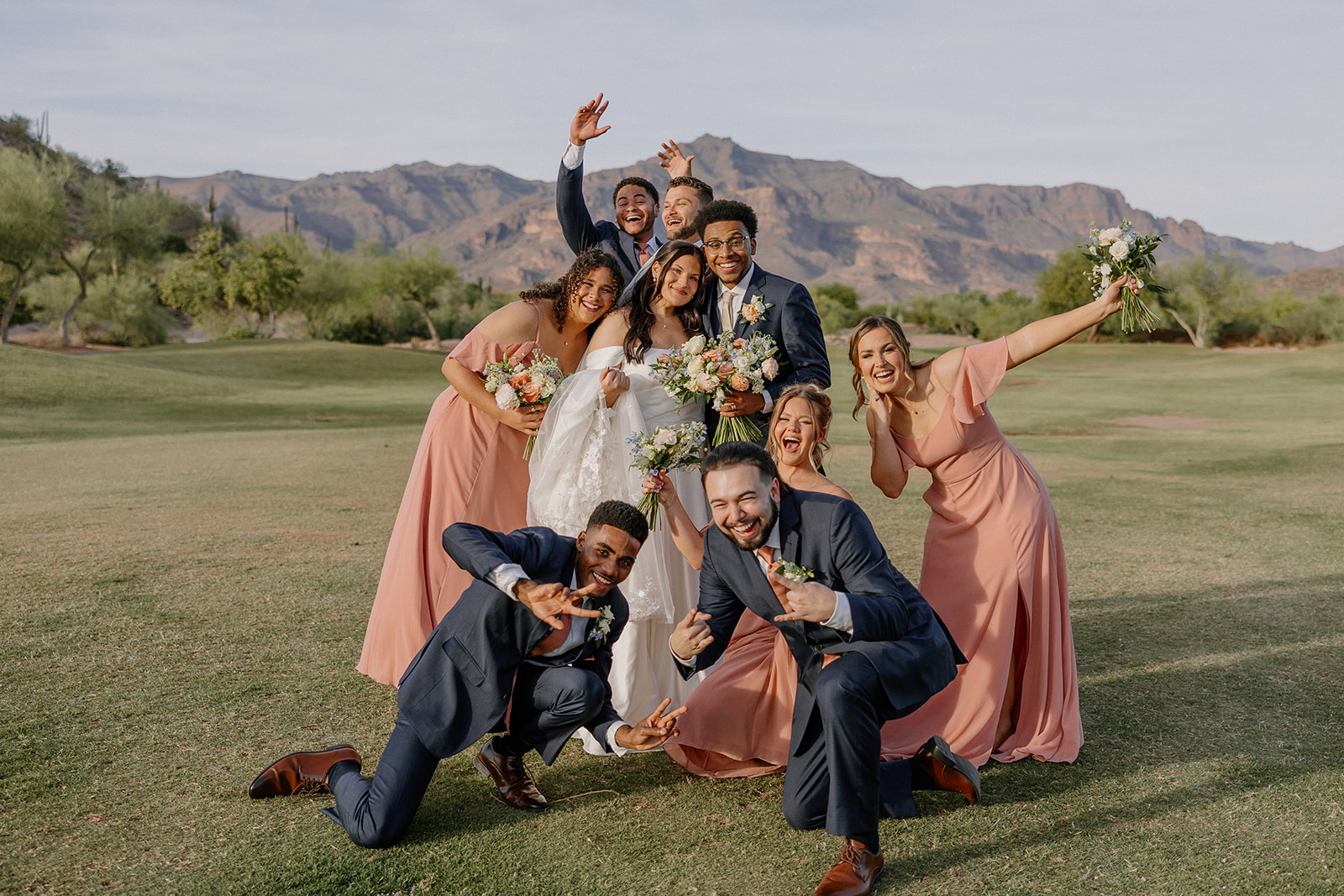 wedding party posing together outdoors with mountains behind them at gold canyon golf resort wedding