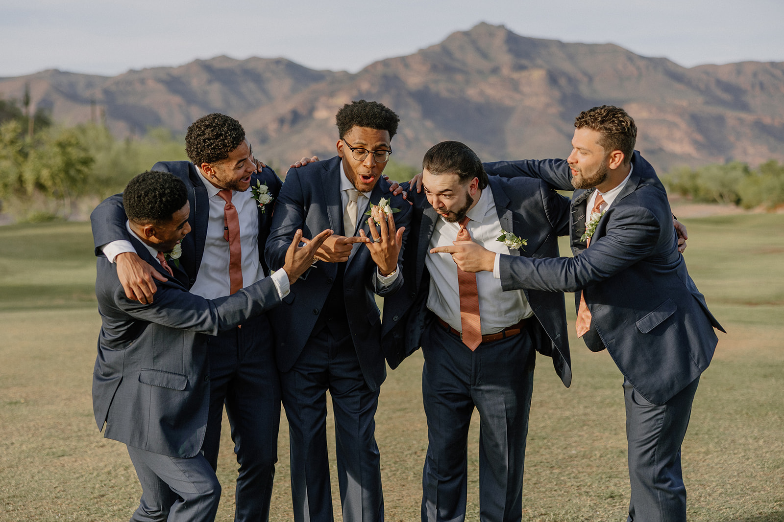 groomsmen joking around together during portraits on golf course