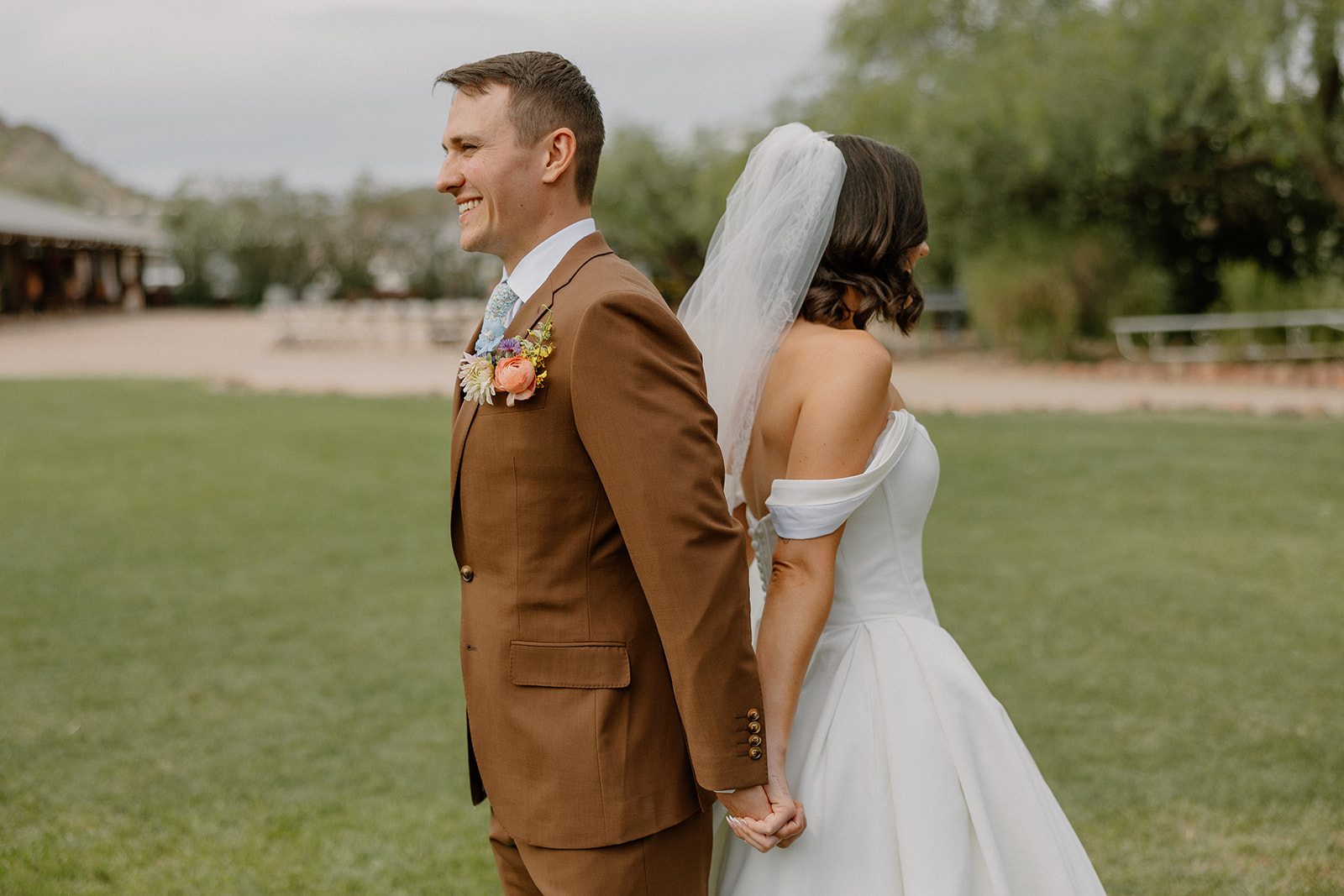 A bride and groom standing back to back for a first touch
