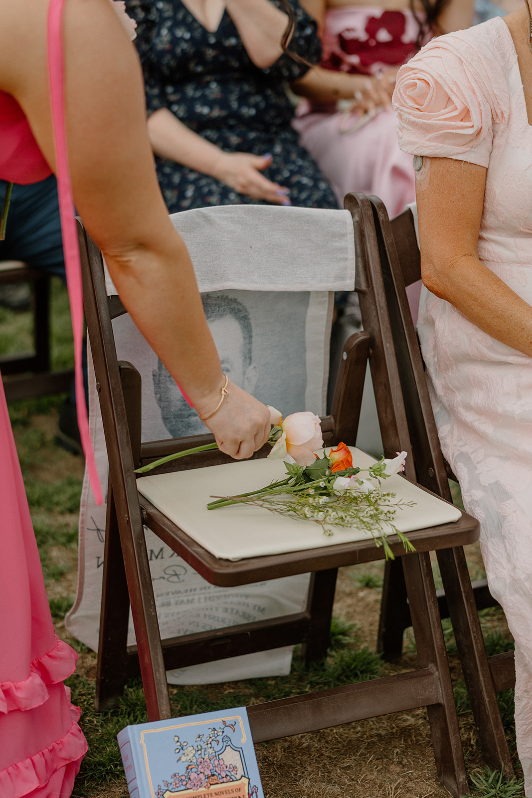 Bridesmaids putting flowers in a chair reserved for the bride's late father as a wedding detail